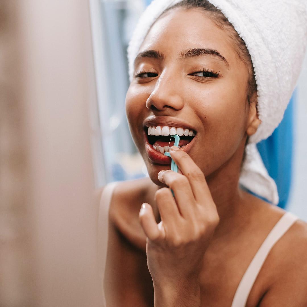 Fotografía de una joven sonriendo con hilo dental